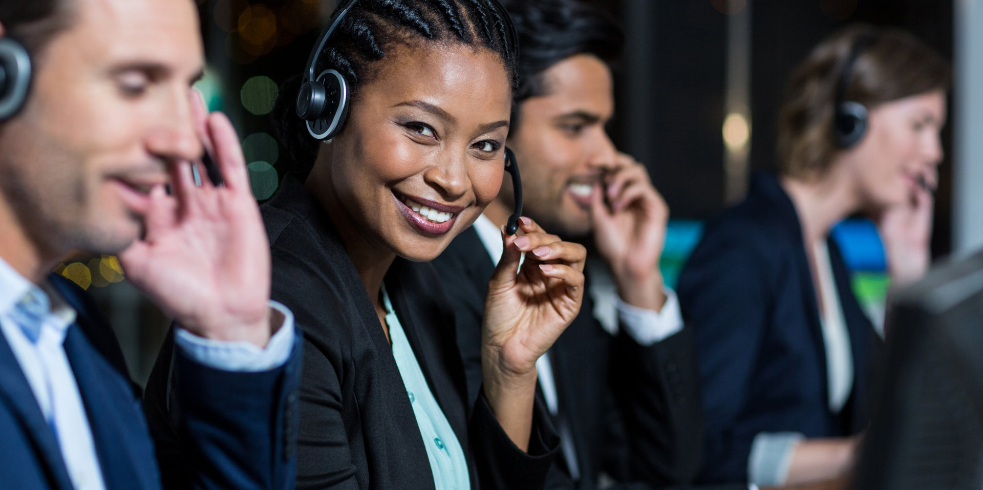 Portrait of businesswoman with headsets using computer at office desk