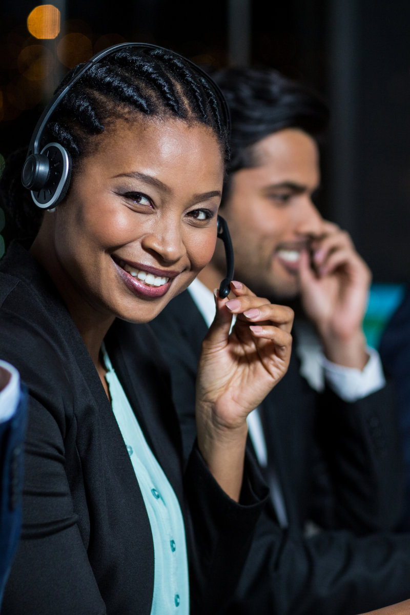 Portrait of businesswoman with headsets using computer at office desk