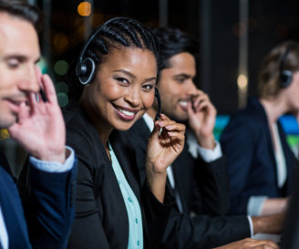 Portrait of businesswoman with headsets using computer at office desk